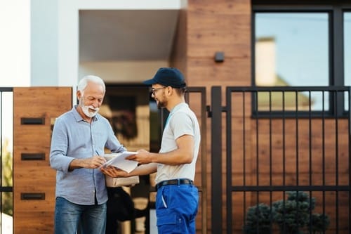 man-signing-paperwork-front-his-house